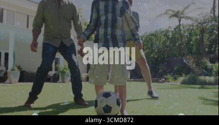Giocare a calcio per famiglie di tre generazioni nel cortile di periferia, con recinzione, palma Foto Stock