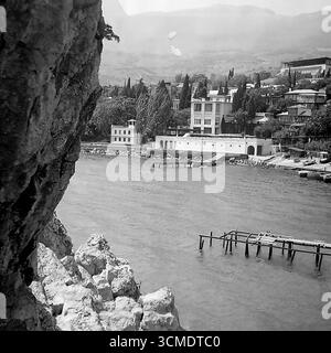 Questa classica fotografia d'archivio degli anni '1970 cattura una vista idilliaca di una località turistica sulla costa meridionale della Crimea, la principale località di villeggiatura sanitaria dell'URSS. Scattato da una scogliera, lo scatto rivela una pittoresca baia con moli e edifici bianchi in sanatorio annidati nel verde lussureggiante sullo sfondo di una montagna. Questo paesaggio è un potente simbolo nostalgico della vacanza estiva sovietica durante l'"era della stagnazione", che trasmette l'atmosfera di serenità e bellezza che milioni di cittadini provenienti da tutto il paese cercavano Foto Stock