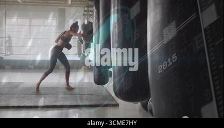 Consegna pugno boxer indossando abbigliamento sportivo che colpisce la borsa di pugno nella palestra di pugilato, con guanti e corde Foto Stock