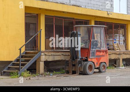 Piccolo carrello elevatore a forche nella parte anteriore del magazzino di stoccaggio del bacino di carico Foto Stock