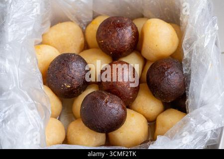 Primo piano di succosi dolci Rasgulla bianchi e neri in una scatola. Questo tradizionale dessert bengalese, noto anche come Rosogolla, è un delizioso, rotondo e sciropposo Foto Stock