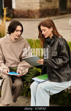 Due giovani si godono un pomeriggio tranquillo all'aperto, studiando insieme e assaporando il momento. Foto Stock