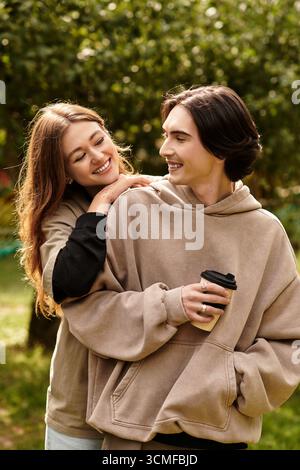 Una coppia amorevole condivide un caldo abbraccio e risate mentre è immersa nella natura. Foto Stock