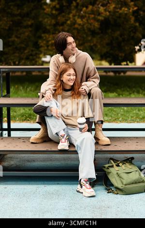 Una giovane coppia condivide un caldo abbraccio seduto su una panchina, circondato dalla natura e dalla gioia. Foto Stock