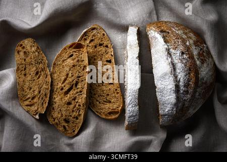 Appetitose fette di pane a base di pasta madre di segale su un panno rustico di lino. Primo piano in stile agriturismo artigianale Foto Stock
