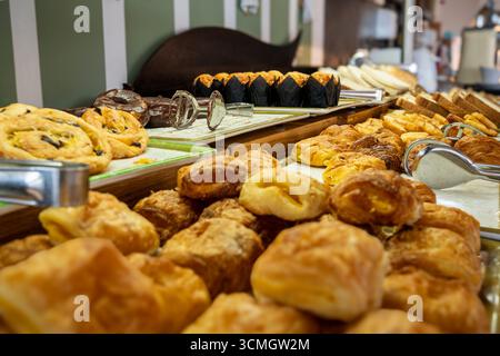 Un tavolo pieno di pasticcini e prodotti da forno. Il tavolo è coperto da una varietà di articoli, tra cui ciambelle, croissant, muffin e altri prodotti da forno. Foto Stock
