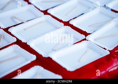 Piatti bianchi con forchette in legno su tovaglia rossa: Ambiente culinario minimalista. Foto Stock