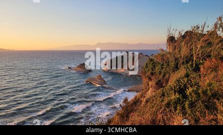 Una vista aerea da sogno e rossastra delle iconiche scogliere di argilla di Capo Drastis al tramonto sull'isola di Corfù, in Grecia Foto Stock