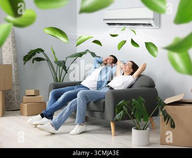 Coppia felice che riposa sul divano a casa. L'aria condizionata mantiene una temperatura confortevole in camera Foto Stock