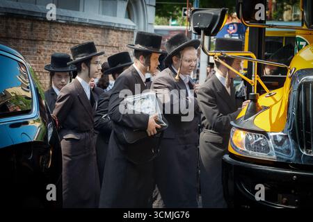 Gli studenti della yeshivah vestiti allo stesso modo salgono su un autobus per portarli a una sessione di preghiera stagionale. A New York. Foto Stock
