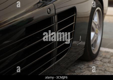 Primo piano di una elegante presa d'aria laterale nera della Ferrari. L'immagine mostra il design lussuoso e il potente motore della vettura. Foto Stock