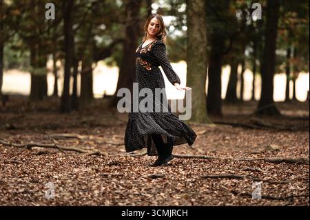 Donna in abito lungo che balla liberamente nella foresta autunnale Foto Stock
