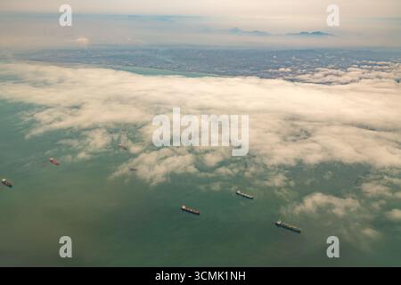 Una vista dell'oceano vicino al porto di Callao, in Perù, con navi da carico in attesa di attraccare sotto un cielo nuvoloso. Foto Stock