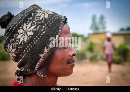 villaggio rurale, ritratto dell'uomo africano vista profilo, di fronte ad una casa, in campagna, indossa un berretto con motivi Foto Stock