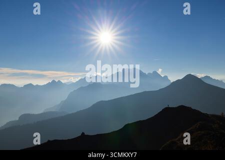 Splendida vista del sole che splende sulla catena montuosa delle Dolomiti italiane, creando un paesaggio mozzafiato Foto Stock