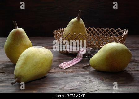 Natura morta con pere mature su un tavolo di legno contro una parete di legno Foto Stock