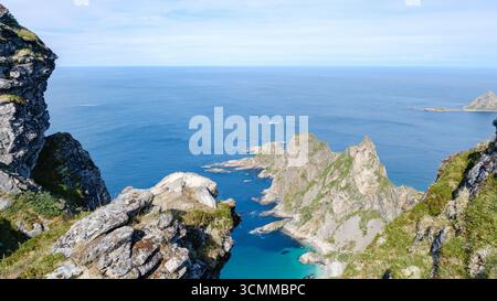 Paesaggio mozzafiato che mostra il monte Matind a Bleik, Andoya, Norvegia. Le maestose scogliere si innalzano drammaticamente dal vibrante oceano blu, offrendo un tranquillo e pittoresco rifugio naturale. Foto Stock