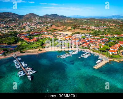 Vista aerea di un affascinante villaggio costiero mediterraneo Porto San Paolo in Sardegna, caratterizzato da acque turchesi, un porticciolo con barche e dintorni Foto Stock