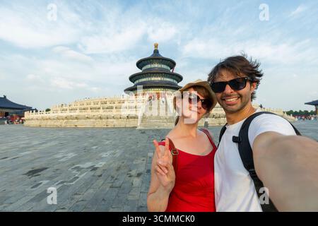 Una coppia di turisti che fa un selfie durante un viaggio. Coppia felice che si diverte in un famoso punto di riferimento di Pechino. Viaggio in Cina, Tempio del Paradiso. Foto Stock