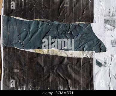 Carta per poster stampata in nero e blu scuro strappata incollata su carta sporca bianca Foto Stock