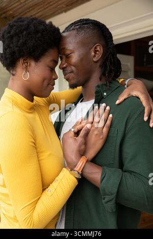 Coppia afroamericana che abbraccia la porta del portico sotto il soffitto di bambù con dolcevita Foto Stock