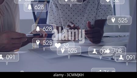 Analizzando le metriche, due professionisti che gestiscono le carte a tavola, con smartphone, biglietto da visita Foto Stock