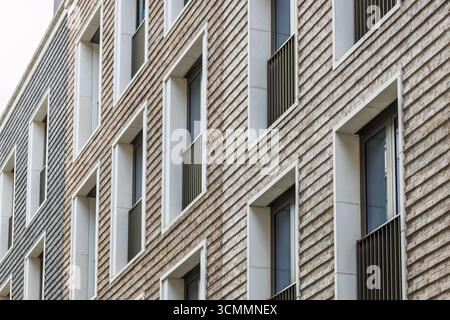 Architettura in muratura contemporanea con rilievi geometrici ritmici in mattoni e finestre incorniciate Foto Stock
