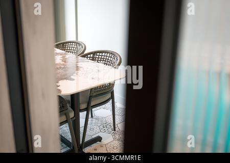 Un assaggio di tavolo da pranzo e sedie attraverso una porta che si apre in un appartamento moderno. Foto Stock