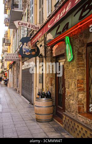 Tipica enoteca francese la grotta a Vins con muro di pietra e una botte e bottiglie fuori in strada. Nizza, Francia - 25 settembre 2021. Foto Stock