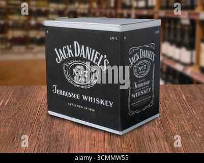 Scatola di cartone con whisky Jack Daniel in piedi su un tavolo di legno in un negozio di vini e liquori con molte bottiglie sugli scaffali. Copenaghen, Danimarca - Foto Stock