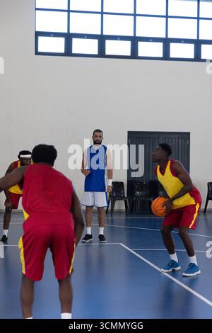 Uomo afro-americano in gilet giallo che tira libero con pallacanestro sul campo, copia spazio Foto Stock