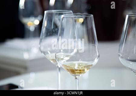 Sul tavolo ci sono tre bicchieri da vino pieni di vino bianco Foto Stock