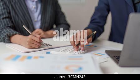 Analisi finanziaria. Professionisti che collaborano ai calcoli del budget utilizzando una calcolatrice. Foto Stock
