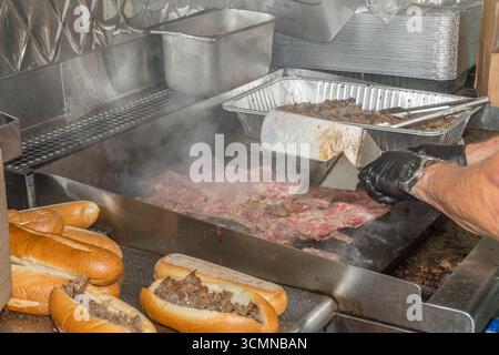 Cottura di panini alla griglia con cheesesteak all'interno di food truck, Philadelphia, Pennsylvania USA Foto Stock