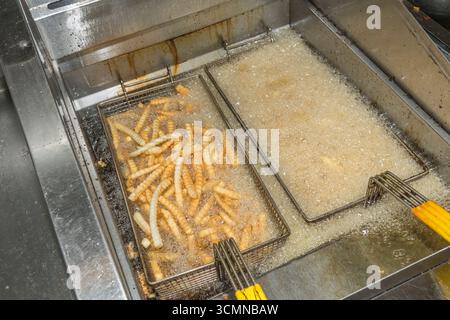 Le patatine fritte vengono cotte in cesti nella friggitrice in un fast food di un ristorante commerciale, Stati Uniti Foto Stock
