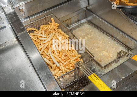 Le patatine fritte vengono cotte in cesti nella friggitrice in un fast food di un ristorante commerciale, Stati Uniti Foto Stock