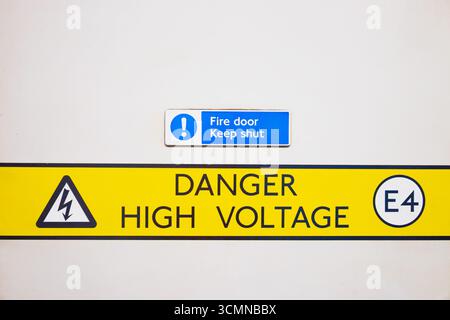Segnale di avvertenza pericolo alta tensione su parete bianca - simbolo di sicurezza dei pericoli elettrici Foto Stock