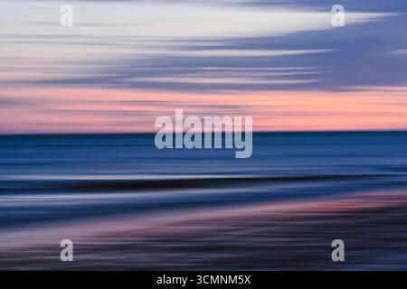 La sfocatura morbida cattura la transizione tranquilla del tramonto sul mare. Foto Stock