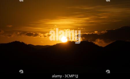 Splendido tramonto che crea una vista estetica in una combinazione di colori rosso, giallo, arancione e motivi che si affacciano sull'oceano, tranquillo e tranquillo Foto Stock