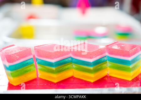 Colorato dessert thailandese a strati chiamato Khanom Chan, esposto in uno stand di cibo di strada, che presenta dolci tradizionali del sud-est asiatico. Foto Stock