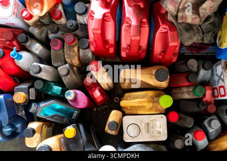 Una vista dall'alto verso il basso di contenitori, caraffe e bottiglie dell'olio motore sporchi e puliti assortiti in vari colori e dimensioni. Foto Stock
