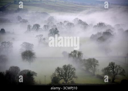 Una coperta di nebbia avvolge Teesdale nella contea di Durham, dove i vuoti rivelano edifici e alberi vicino al villaggio di Cotherstone Foto Stock