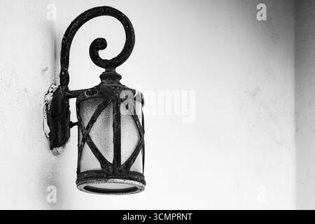 Antica lanterna in ferro battuto in metallo nero appesa al muro di pietra. Lanterna in ferro battuto d'epoca in una casa storica nella città vecchia. Foto di viaggio, nessuno Foto Stock