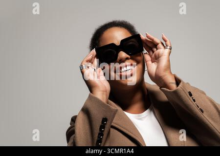 Una donna sicura di sé indossa il suo outfit autunnale mentre sorride in uno studio. Foto Stock