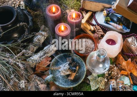Allestimento dell'altare Wiccan incantato con candele bruciate, cristalli, erbe e strumenti rituali per la guarigione spirituale e la pulizia energetica. Foto Stock