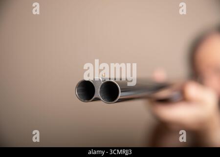 Un uomo ha un fucile con una canna nera e una punta rossa Foto Stock