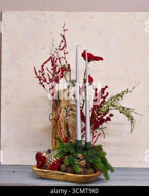 Festività natalizie con cardinali rossi, candele, rami di pino, bacche e ornamenti. Vacanza rustica che crea un ambiente caldo e commerciale Foto Stock
