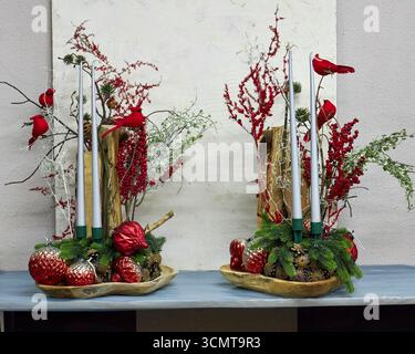 Festività natalizie con cardinali rossi, candele, rami di pino, bacche e ornamenti. Vacanza rustica che crea un ambiente caldo e commerciale Foto Stock