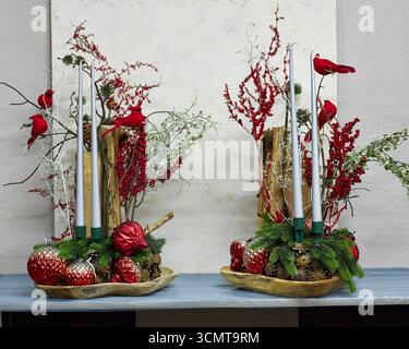 Festività natalizie con cardinali rossi, candele, rami di pino, bacche e ornamenti. Vacanza rustica che crea un ambiente caldo e commerciale Foto Stock