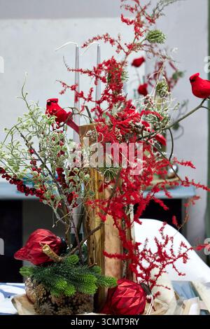 Festività natalizie con cardinali rossi, candele, rami di pino, bacche e ornamenti. Vacanza rustica che crea un ambiente caldo e commerciale Foto Stock